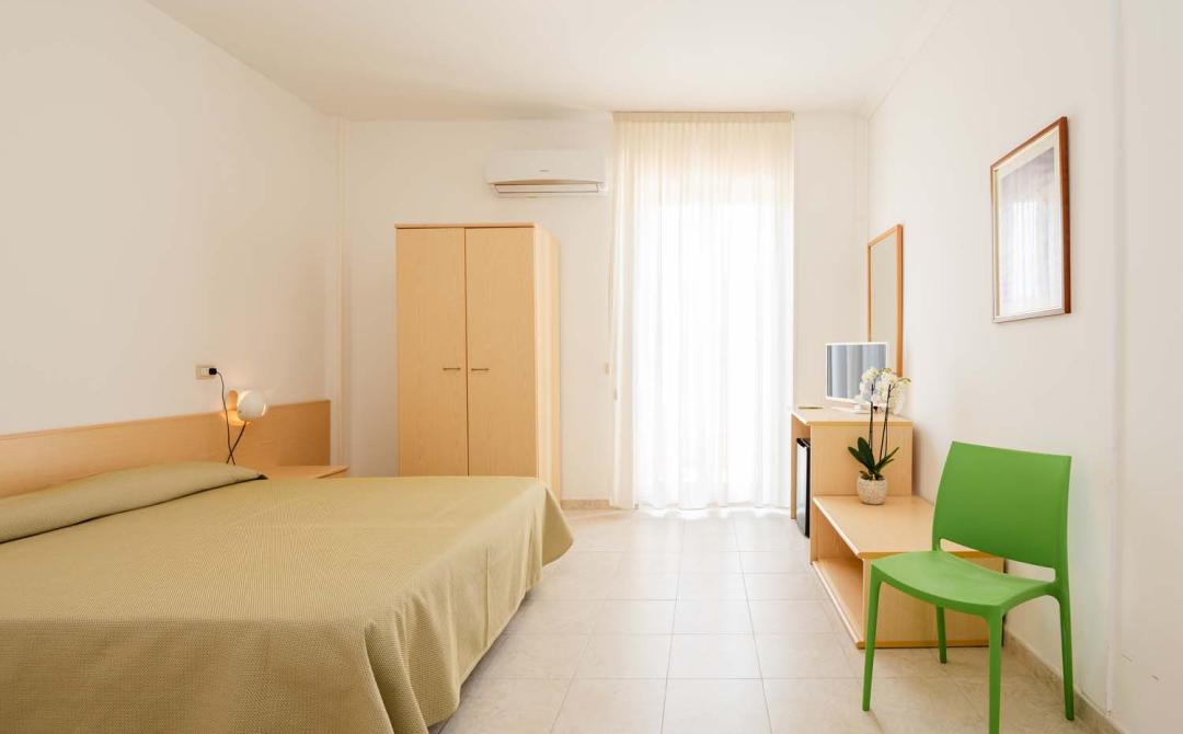 Helles, minimalistisches Zimmer mit grünem Stuhl und weißen Blumen.