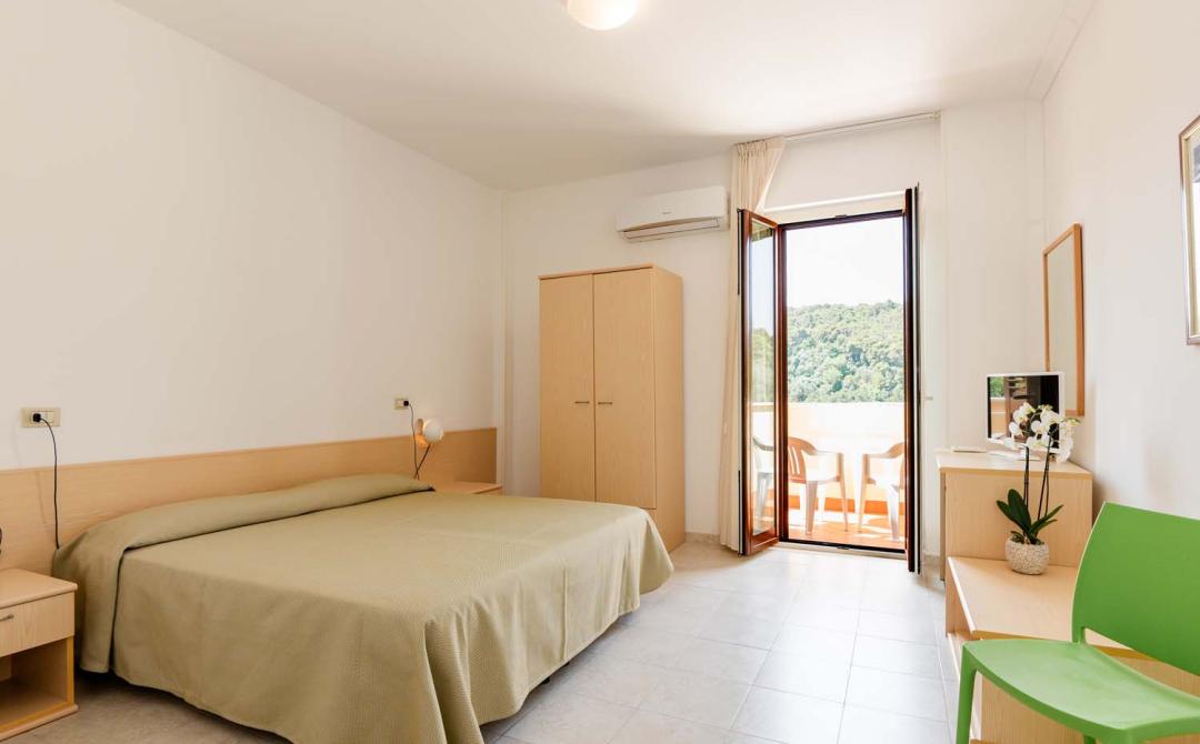 Helles Zimmer mit Doppelbett, Naturblick und modernen Möbeln.