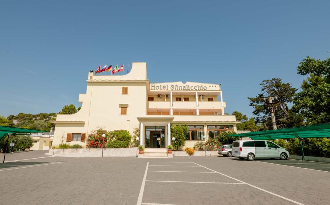 Hotel luminoso con bandiere, atmosfera accogliente e giardino fiorito.