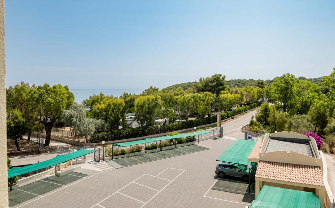 Vista serena sul mare, alberi verdi e parcheggio tranquillo.